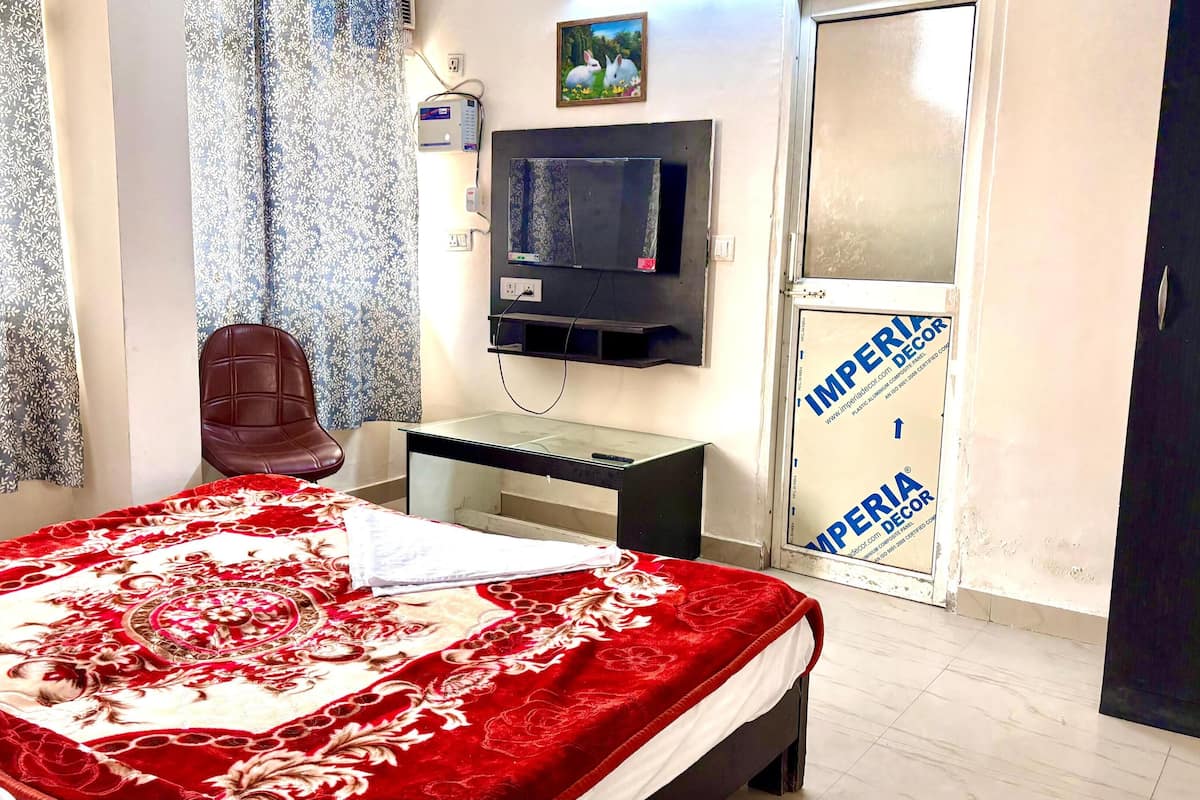 Ein Schlafzimmer mit Bett, Sessel, Fernseher und einer Tür mit einem Schild.