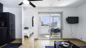 Un espacio habitable compacto con kitchenette, comedor y balcón con vistas.