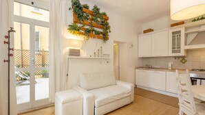 A modern kitchen with white cabinets, a white dining table, and a white sofa. - Located on the second floor of a typical Milanese condominium, this two-room apartment combines comfort and contemporary style. The flat features a fully equipped kitchen, ideal for those who love to cook and host. You will find a hob, oven, fridge, dish (Milano)