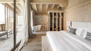 Une chambre à coucher moderne avec un grand lit, un dressing et une baignoire.