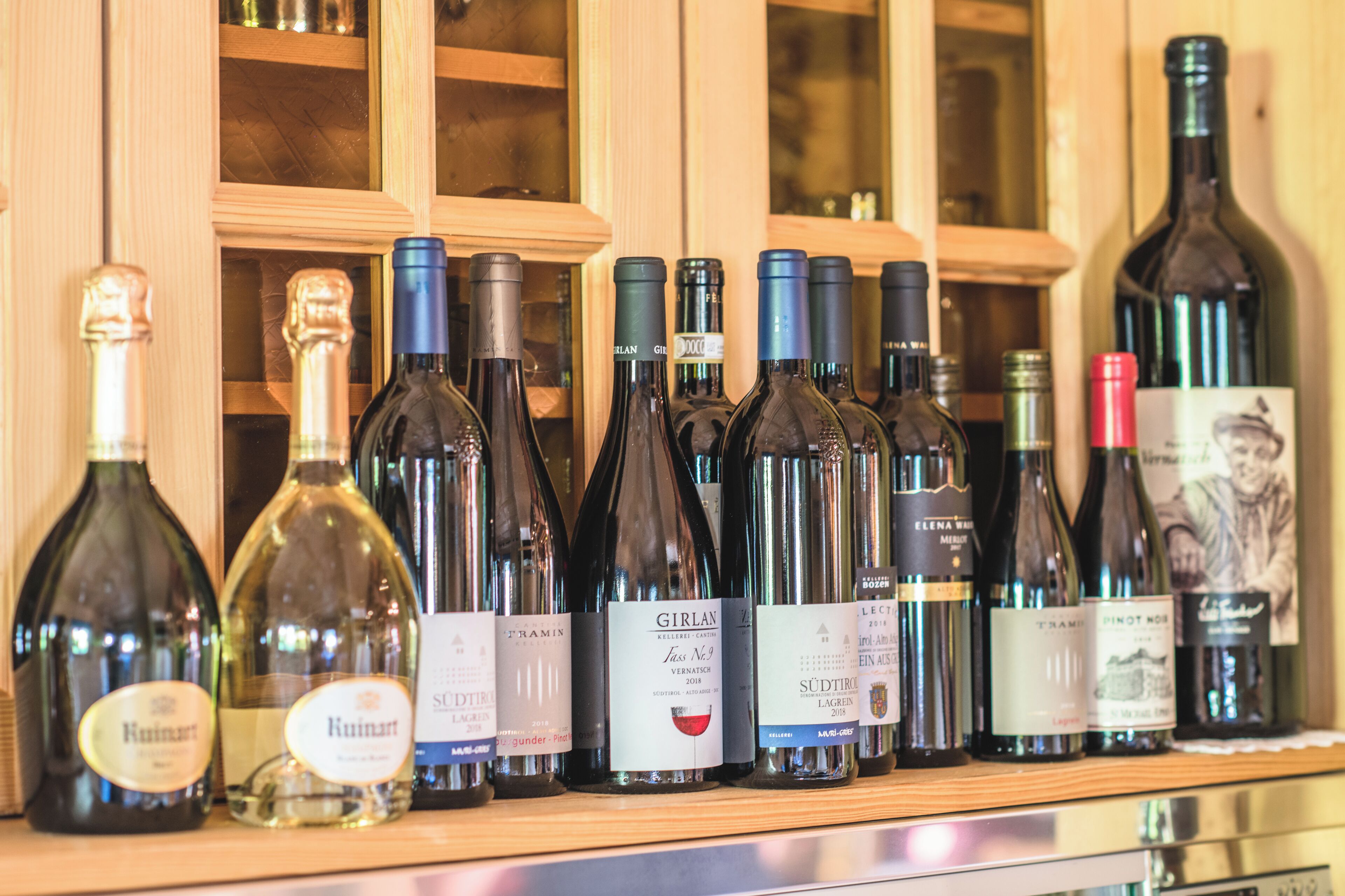 A variety of wine bottles displayed on a wooden shelf.