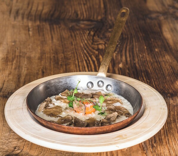 A copper pan with a wooden handle on a wooden table. - Muliné Lodge (Selva di Val Gardena)