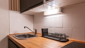Eine Küche mit Spüle aus Edelstahl, einer Holz Arbeitsplatte und einem schwarzen Geschirrgestell.