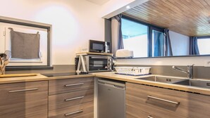 A modern kitchen with wooden cabinets, a dishwasher, a microwave, and a sink. - Alpine Comfort at Chamrousse (Chamrousse)