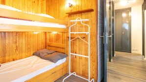 A bunk bed with a wooden headboard, a white metal hanger rack, and a wooden floor. - Alpine Comfort at Chamrousse (Chamrousse)