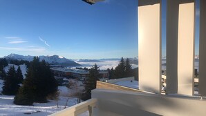 A balcony with a view of snow-covered mountains and a town below. - Alpine Comfort at Chamrousse (Chamrousse)