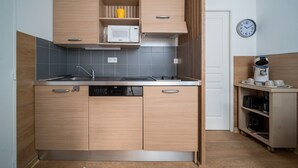 Kompakti keittiö, jossa on puukalusteet, mikroaaltouuni ja kahvinkeitin.