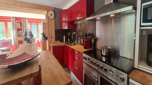 Una cocina moderna con armarios rojos, electrodomésticos de acero inoxidable y una mesa de comedor de madera.
