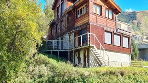 Eine Holzhütte mit Steinunterbau, einem Balkon und einer Treppe zum Obergeschoss.