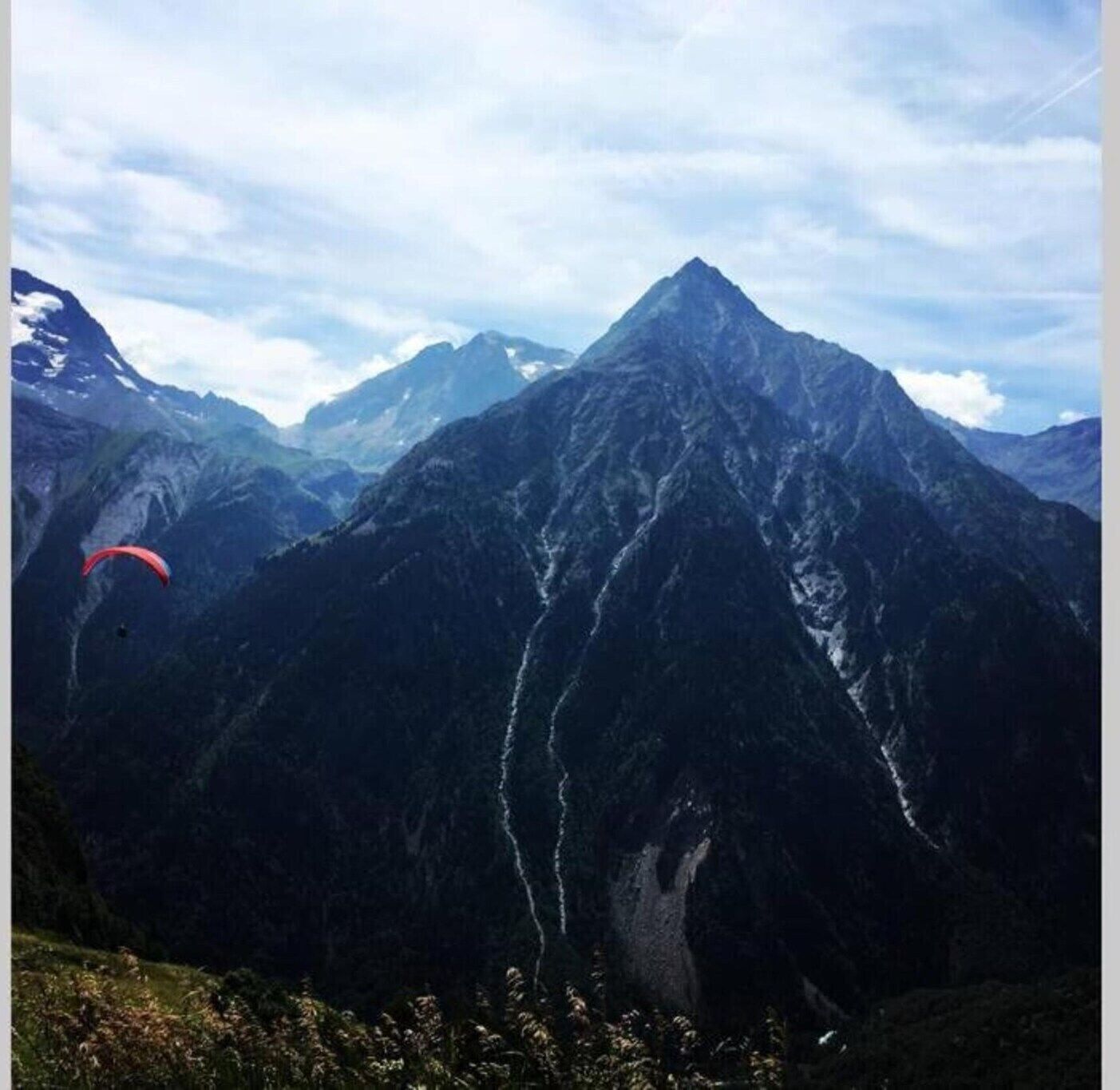 Un paisaje montañoso con una persona parapentando.