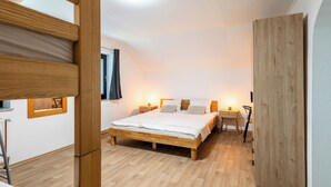 Ein Schlafzimmer mit einem hölzernen Bett, Nachttischen, einem Schrank und einem Fenster mit Vorhängen.