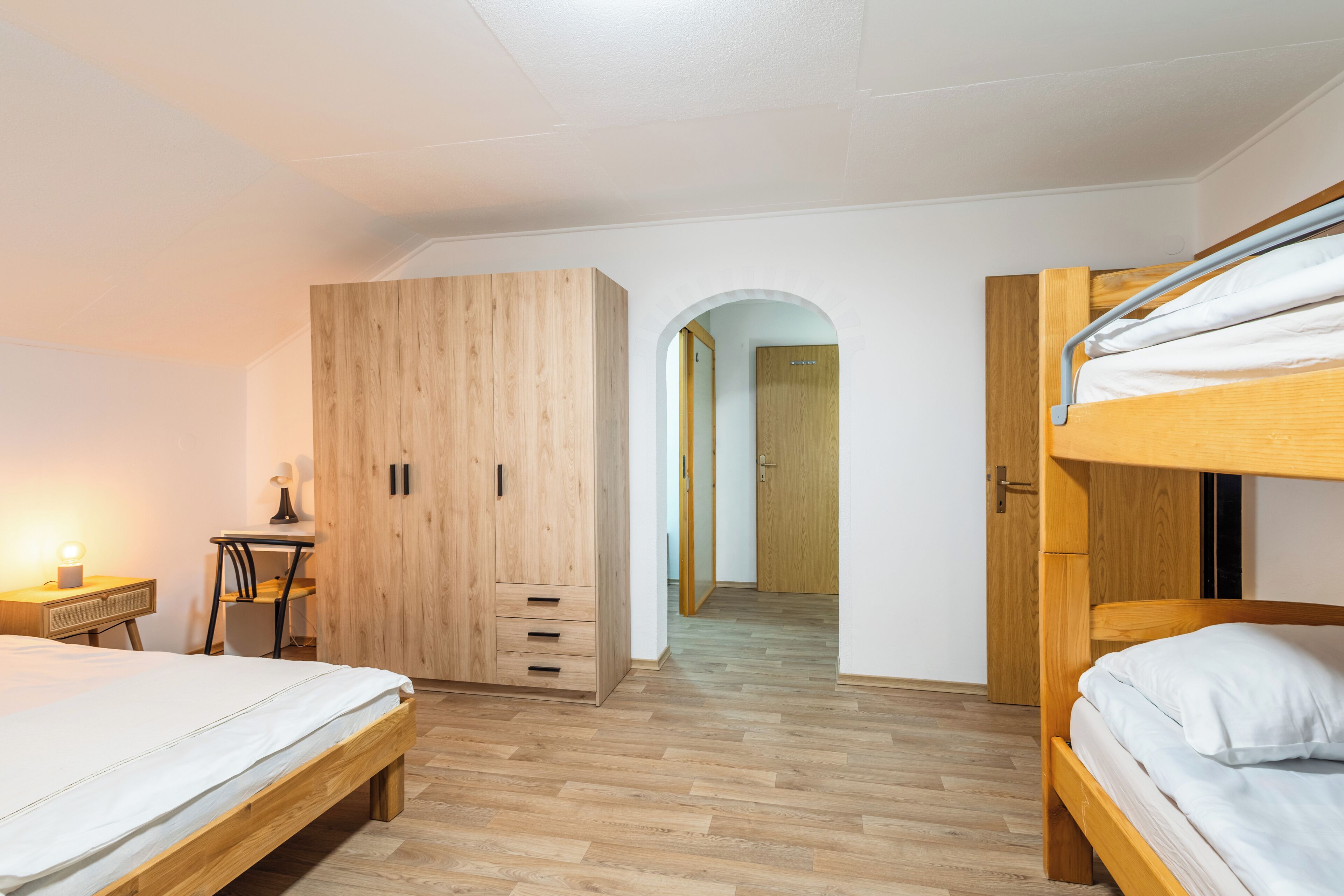 Un dormitorio con dos camas, un armario de madera, un escritorio y una silla.