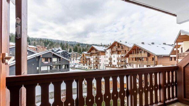 A wooden balcony with a view of a ski resort.