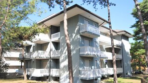 A multi-story apartment building with balconies and a covered outdoor area. - Stylish retreat in a central area (Lignano Sabbiadoro)