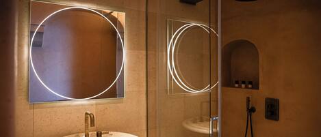 A bathroom with a round mirror, a sink, and a shower.
