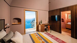 A modern bedroom with a large bed, a desk, and a TV. There is a view of the ocean through a large window. - Antalia Boutique Hotel (Positano)