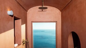 A narrow hallway with a wooden floor leading to a large window with a view of the ocean. - Antalia Boutique Hotel (Positano)