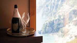 A bottle of champagne and two glasses on a tray by a window overlooking a mountainous landscape. - Antalia Boutique Hotel (Positano)