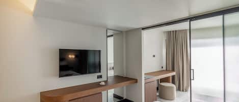 A modern hotel room with a large bed, a TV mounted on the wall, a wooden console table, and a large window with curtains.
