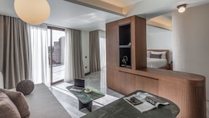 A modern hotel room with a large bed, a desk, a laptop, and a view of the city through the window.