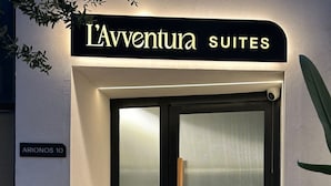 A hotel entrance with a sign reading "L'Adventure Suites" and a door with a frosted glass panel.