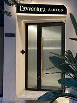 A hotel entrance with a sign reading "L'Adventure Suites" and a door with a frosted glass panel.