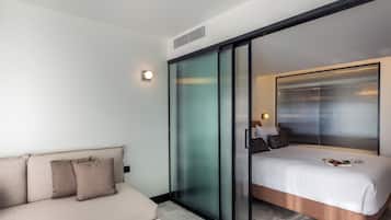 Una habitación de hotel moderna con cama, sofá y puerta corredera de vidrio.