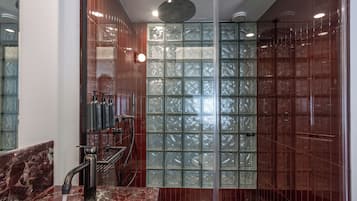 Un baño moderno con cabina de ducha de bloque de vidrio, encimera de mármol y ducha a la vista.