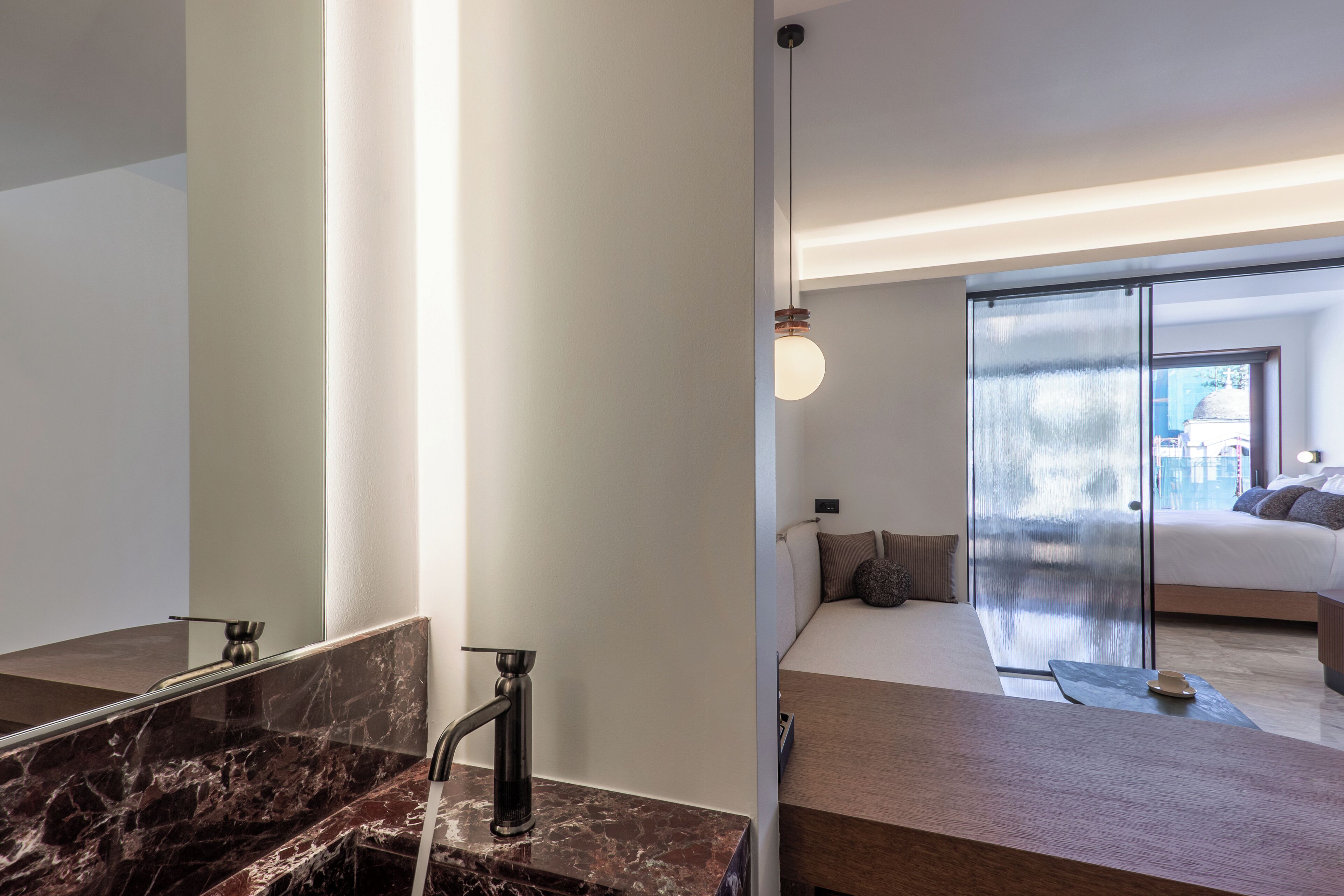 A modern bathroom with a marble sink, a large mirror, and a hanging light fixture.
