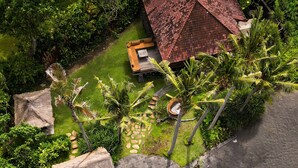 An aerial view of a resort with a swimming pool, lounge area, and a thatched-roof structure. - A hidden gem, away from the hustle and bustle of everyday life. (Karangasem)