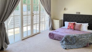 A bedroom with a large window, a bed with a fluffy blanket, and a chandelier. - Templestowe Luxe Retreat | Pool, Tennis Court & Private Oasis (Templestowe)