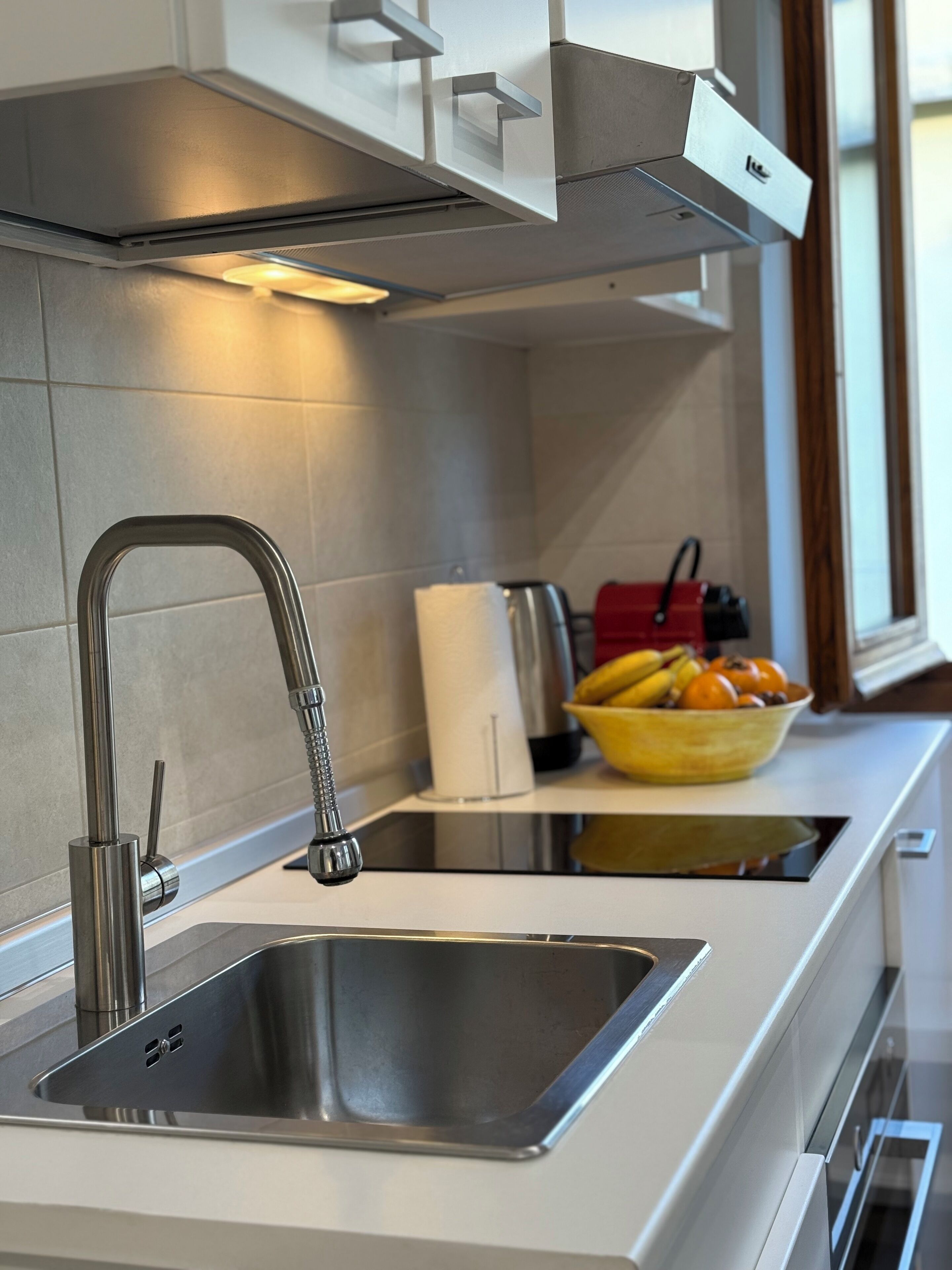 Una cucina moderna con lavello in acciaio inossidabile, forno integrato e finestra che offre luce naturale.