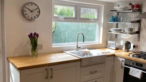 Una cocina con encimera de madera, un lavamanos, una estufa y un reloj en la pared.