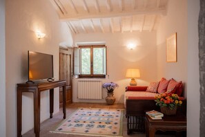 A cozy living room with a television, a sofa with cushions, a lamp, and a window with a view. - My Exclusive Italy - Authentic Chianti's Villa with Private Pool and view (Panzano In Chianti)
