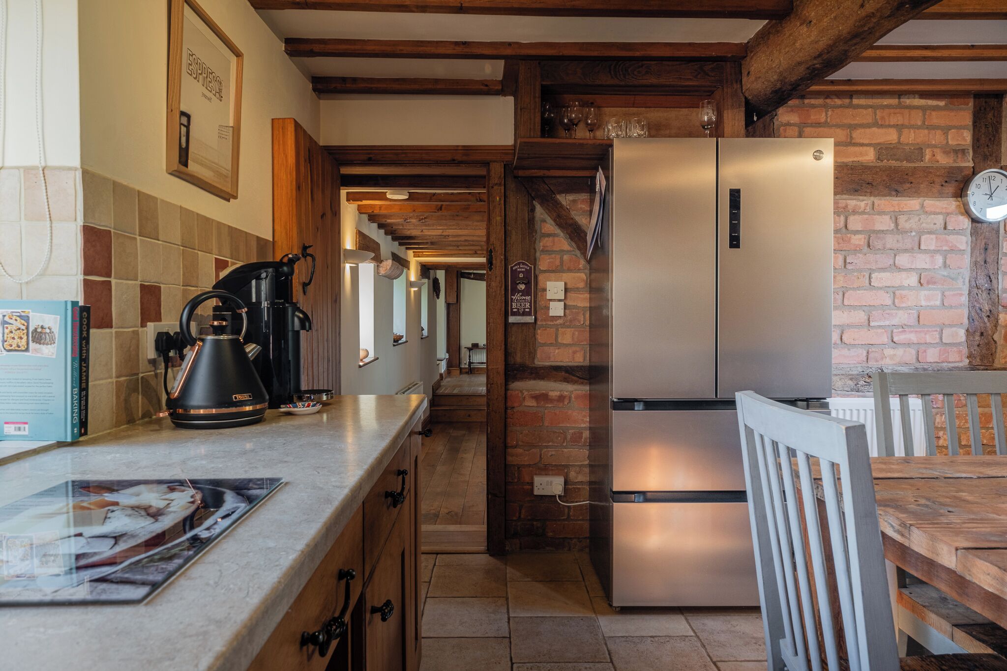 A kitchen with a stainless steel refrigerator, a coffee maker, and a tiled backsplash.