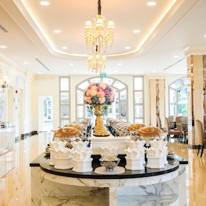 A hotel lobby with a marble reception desk, a chandelier, and a floral centerpiece. - LK Grand Empire (Pattaya)