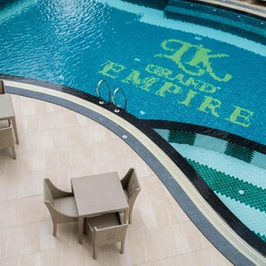 A pool with a tiled edge and a chair and table set up on the deck. - LK Grand Empire (Pattaya)