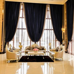 A luxurious room with a large window, elegant furniture, and a chandelier. - LK Grand Empire (Pattaya)