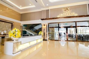 A hotel lobby with a reception desk, a staircase, and a dining area. - LK Grand Empire (Pattaya)