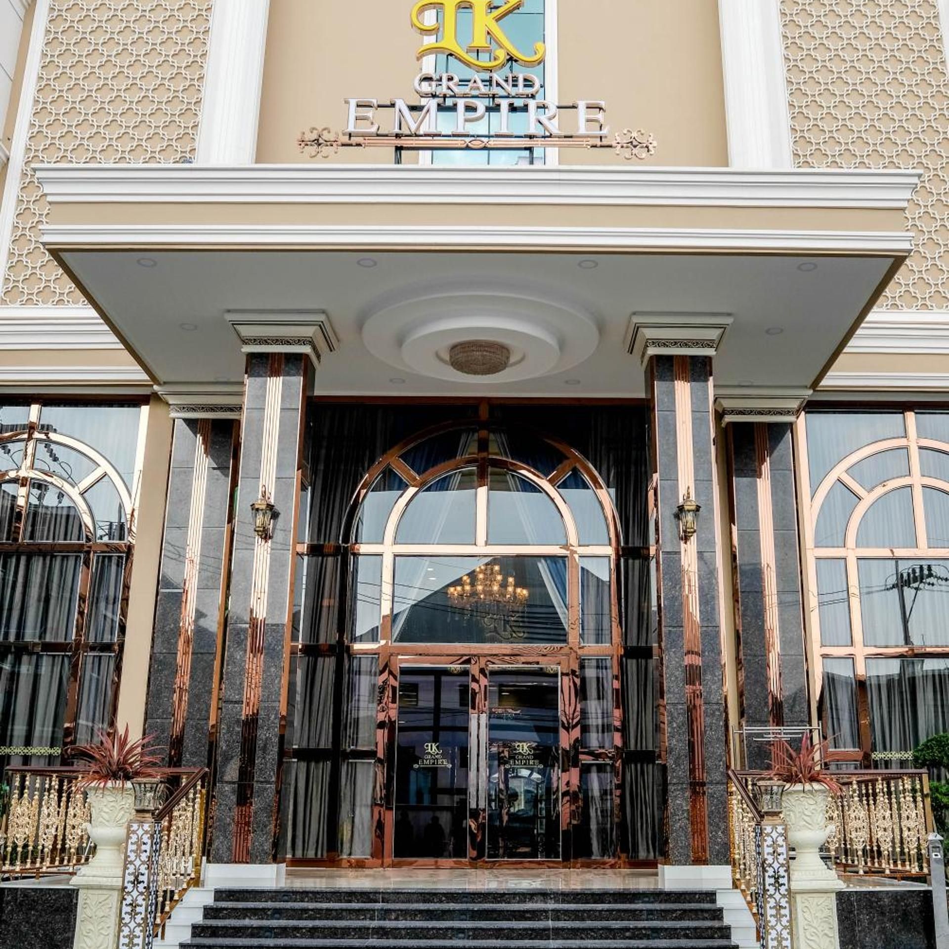 A grand entrance with a large arched doorway, a prominent sign above reading 'GRAND EMPIRE,' and a symmetrical facade with decorative columns and railings.