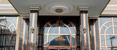 Una entrada imponente con un amplio arco, un cartel destacado que dice 'GRAND EMPIRE' y una fachada simétrica con columnas y barandillas decorativas.
