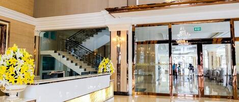 A grand entrance with a reception desk, a staircase, and a sign reading 'TK GRAND EMPIRE'.