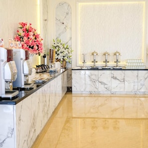 A marble reception desk with a coffee machine, a vase of flowers, and a wall-mounted light fixture.