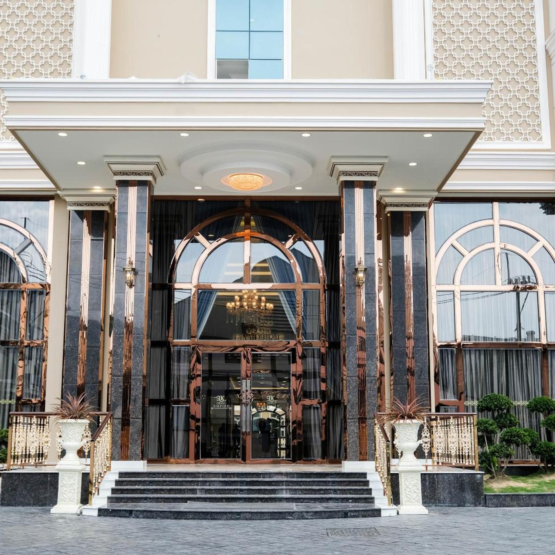 A grand entrance with a large archway, steps leading up to it, and a chandelier above.