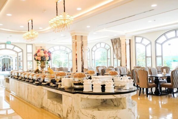 A buffet area with a marble counter, chandeliers, and seating arrangements. - LK Grand Empire (Pattaya)