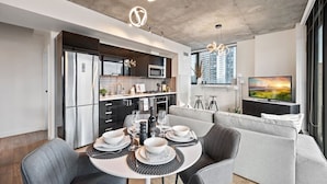 A modern kitchen with a dining area, a sofa, and a TV.