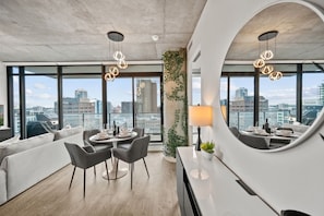 Uma sala de estar moderna com área de jantar, janelas amplas e vista para a cidade.