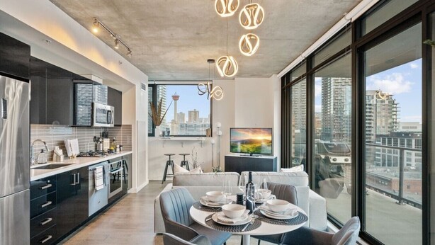 A modern kitchen with a large window, a dining area with a table set for two, and a city view.