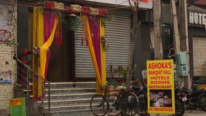 A building with a sign reading "Ashoka's Banquet Hall Hotels Rooms Restaurant."