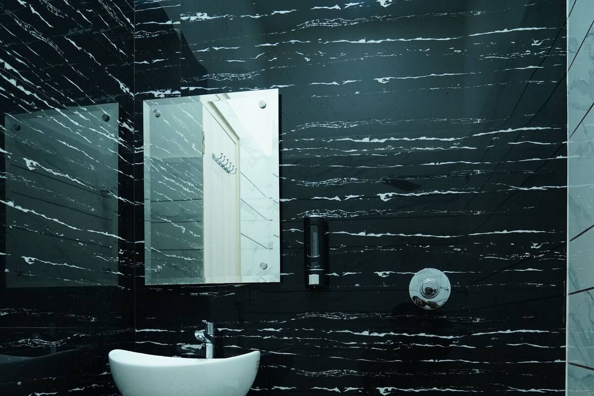 Ein Badezimmer mit Wandverkleidung aus Schwarz-Weiß-Marmor, einem weißen Waschbecken und einer Toilette.